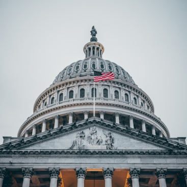 An american flag centered in front of the capitol building.